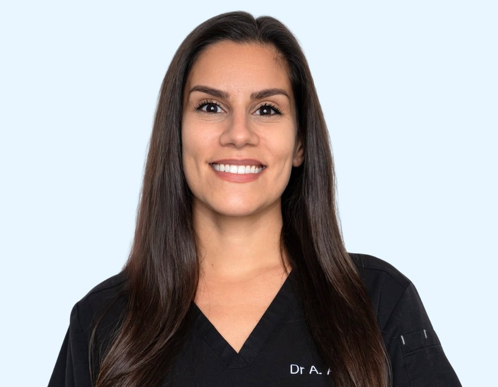 Dentiste souriante avec veste médicale noire, représentant le centre de soins dentaires Swiss Clinics, expert en implants, blanchiment dentaire et soins esthétiques dentaires.